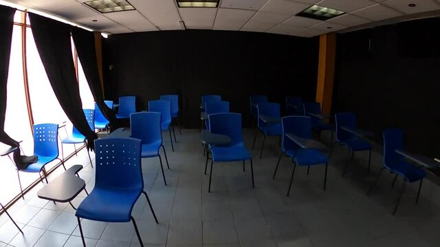 Aula escolar con fondo negro y sillas azules en interior de escuela