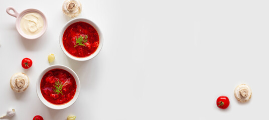 Traditional home Ukrainian beet soup with fresh green dill. Russian borscht in a bowl of tomatoes, sour cream, and mushrooms on a white background with minespace.