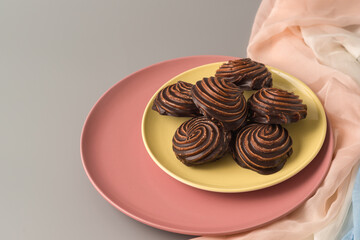 Traditional Russian vanilla marshmallows in chocolate glaze in pink and yellow plates on gray background