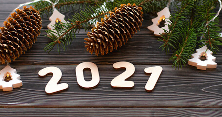 Christmas tree branches with a garland and the number 2021 on a dark wooden background. Happy new year to 2021. Banner.