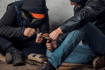 Fototapeta na wymiar two shabby men preparing drug injection in slums