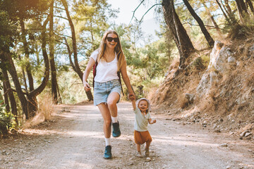 Mother with child daughter walking in forest family vacation mom travel with baby hiking together...