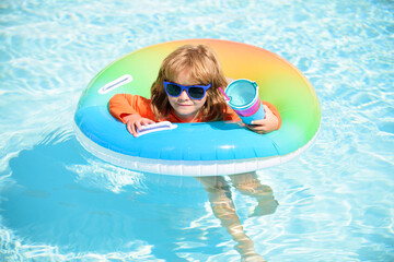 Kid in swimming pool, relax swim on inflatable ring and has fun in water on summer vacation.