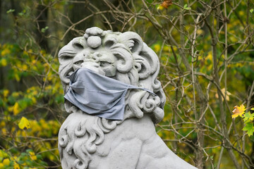sculpture of a gray stone lion wearing a protective mask