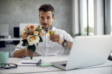 Mid adult businessman drinking wine while having online date over laptop.