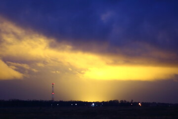 Light pollution by illuminated greenhouses at early morning. Glowing clouds.