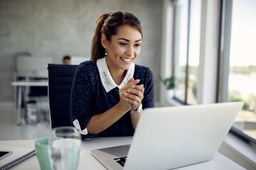 Happy businesswoman reading an e-mail on laptop in the office.