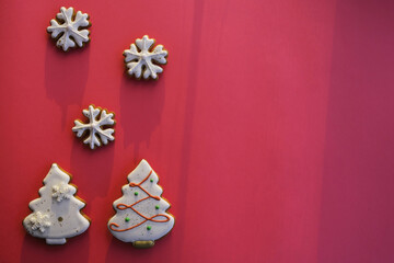 Fototapeta na wymiar Christmas gingerbreads in the form of trees and snowflakes on a pink background. Composition with empty space for text; top view, flat lay.