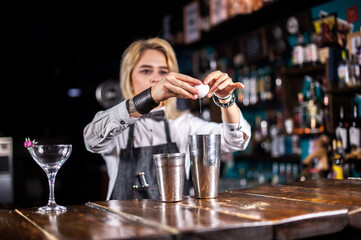 Girl bartender makes a cocktail at the brasserie