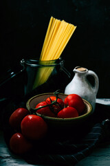 Uncooked spaghetti,  organic tomatoes and jug of olive oil