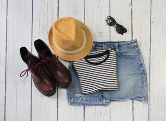 Still life of clothes, denim mini skirt, striped t-shirt and hat, on a white wooden background