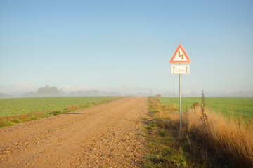 An old country asphalt road through the village in a fog. Street sign close-up. Clear blue sky....
