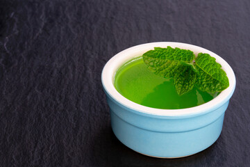 Mint jelly in small pot on black stone background