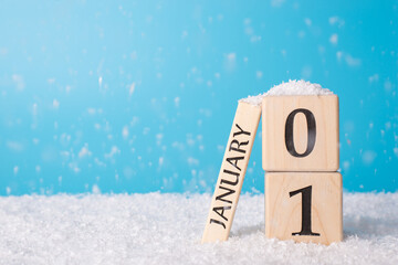 The first day of a new year concept. Close up photo of wooden cube calendar showing date of a new year isolated on blue background with snowfall - Powered by Adobe
