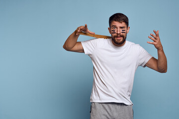 emotional man with a bat in his hand on a blue background and makeup on his face black lines energy t-shirt baseball