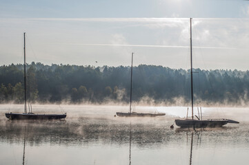 Żaglówki o poranku na jeziorze podczas mgły