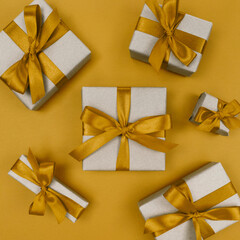Gift boxes wrapped in craft paper with yellow ribbons and bows. Festive monochrome flat lay.