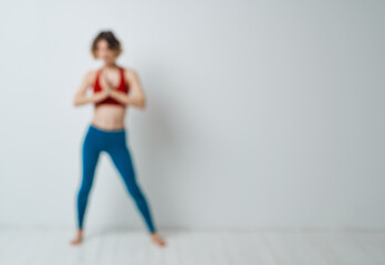 Obraz premium woman doing yoga in a bright room and blue leggings red tank top