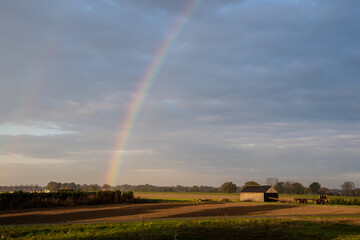 Rainbow over stormy sky. Rural landscape with rainbow over dark stormy sky in a countryside at autumn day