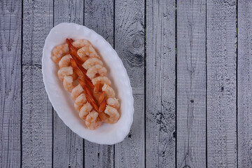 Shrimp on a white plate top view on a light wooden table