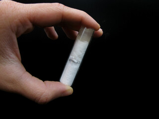 A transparent test tube with white powder in someone's hands. Mirabilite. Sal glauberi.