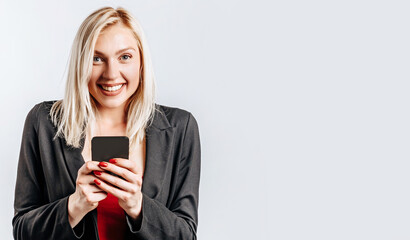 Beautiful young cute girl smiling and holding phone on gray isolated background