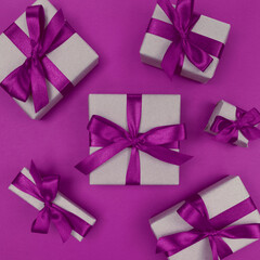 Gift boxes wrapped in craft paper with purple ribbons and bows. Festive monochrome flat lay.