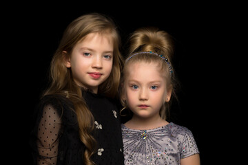 Two little girls posing in the studio on a black background. Style and fashion concept.