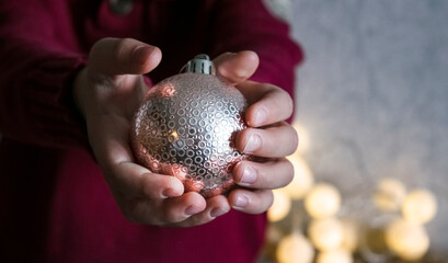 A shiny New Year's ball in the hands of a child. The concept of New Year and Christmas holidays, preparation for the new year.