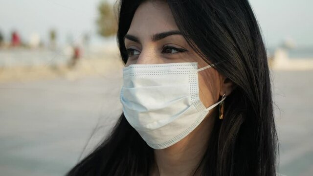 brunette Girl in mask in outdoor look to the mobile phone and wear the mask