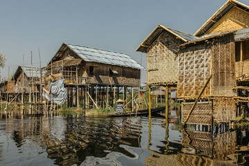 Fototapeta na wymiar Floating village of Inle Lake is one of the most spectacular destinations and features of Myanmar.Rural lifestyle in Asia.Fishermen simple houses.People on boat. Traditional bamboo buildings.