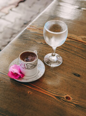 Turkish coffee with a glass of water and a pink flower
