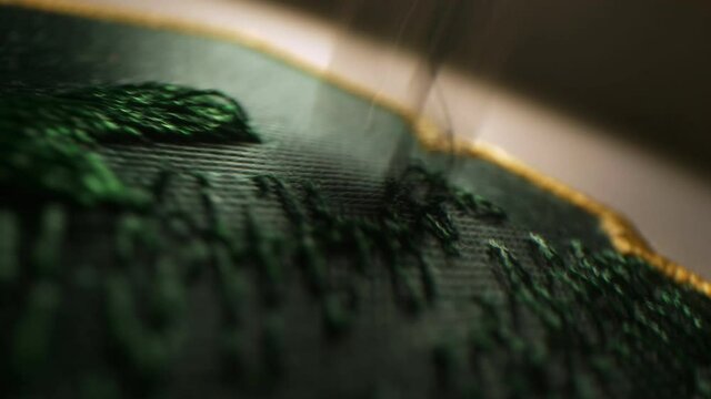 Machine embroiders pattern of hockey team logo in workshop