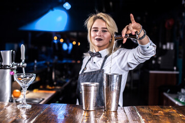 Girl bartender makes a cocktail on the saloon