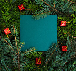 Fototapeta na wymiar Creative layout made of christmas tree branch with paper card note and Christmas gifts. Flat lay, top view 