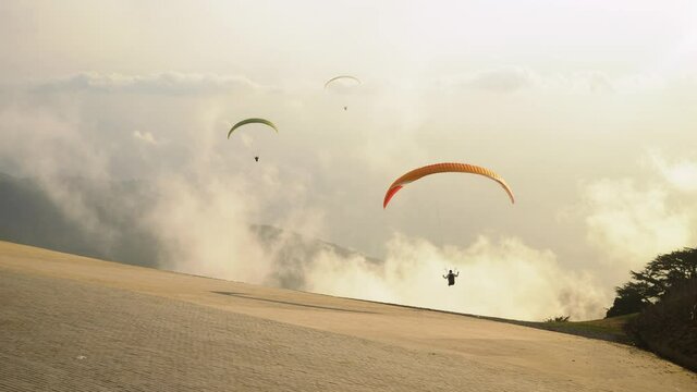 Paragliders prepareing to take off from a mountain. Paragliding in the sky at evening sunset in sea background. Extreme sport