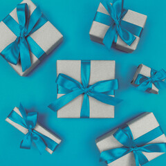 Gift boxes wrapped in craft paper with blue ribbons and bows. Festive monochrome flat lay.