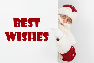 Santa Claus points his fingers at the board with the text - BEST WISHES