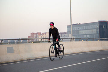 Obraz premium The girl rides a bicycle over the bridge. Morning workout in the city on a bike. Krestovsky Island St. Petersburg.