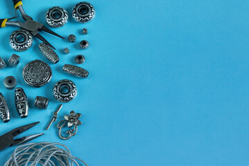 A set of silver accessories and tools for making jewelry on a blue background. Needlework.