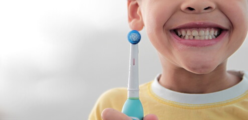 little boy brushing his teeth with an electric tooth brush with grey background stock photo