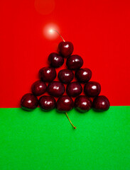 wet cherries laid out in the shape of a triangular - Christmas tree - on a red-green background of velvet paper