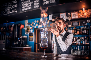 Professional bartender decorates colorful concoction while standing near the bar counter in nightclub