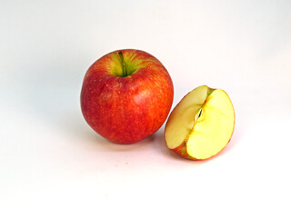 Whole apple with a slice of apple next to it.      