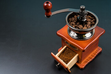 Coffee grinder with beans on black background, making coffee