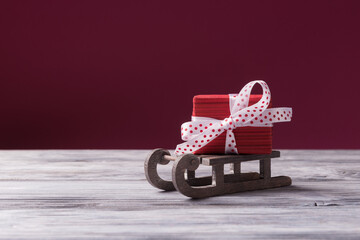 Santa's sleigh with red gift box against pink background with copy space. Christmas and New Year concept