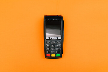 Payment terminal isolated on orange background. A contactless device for paying for purchases with...