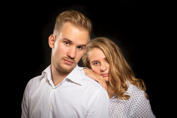 Young beautiful couple studio portrait on black background.