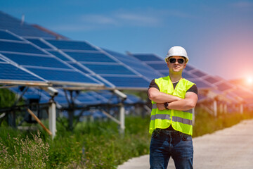 Engineer in sun glasses and helmet on a background of solar energy power station.