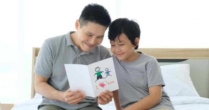 Happy father's day! Son surprise dad and giving I LOVE DAD card. Dad and son smiling and hugging They spend their free time together happily.